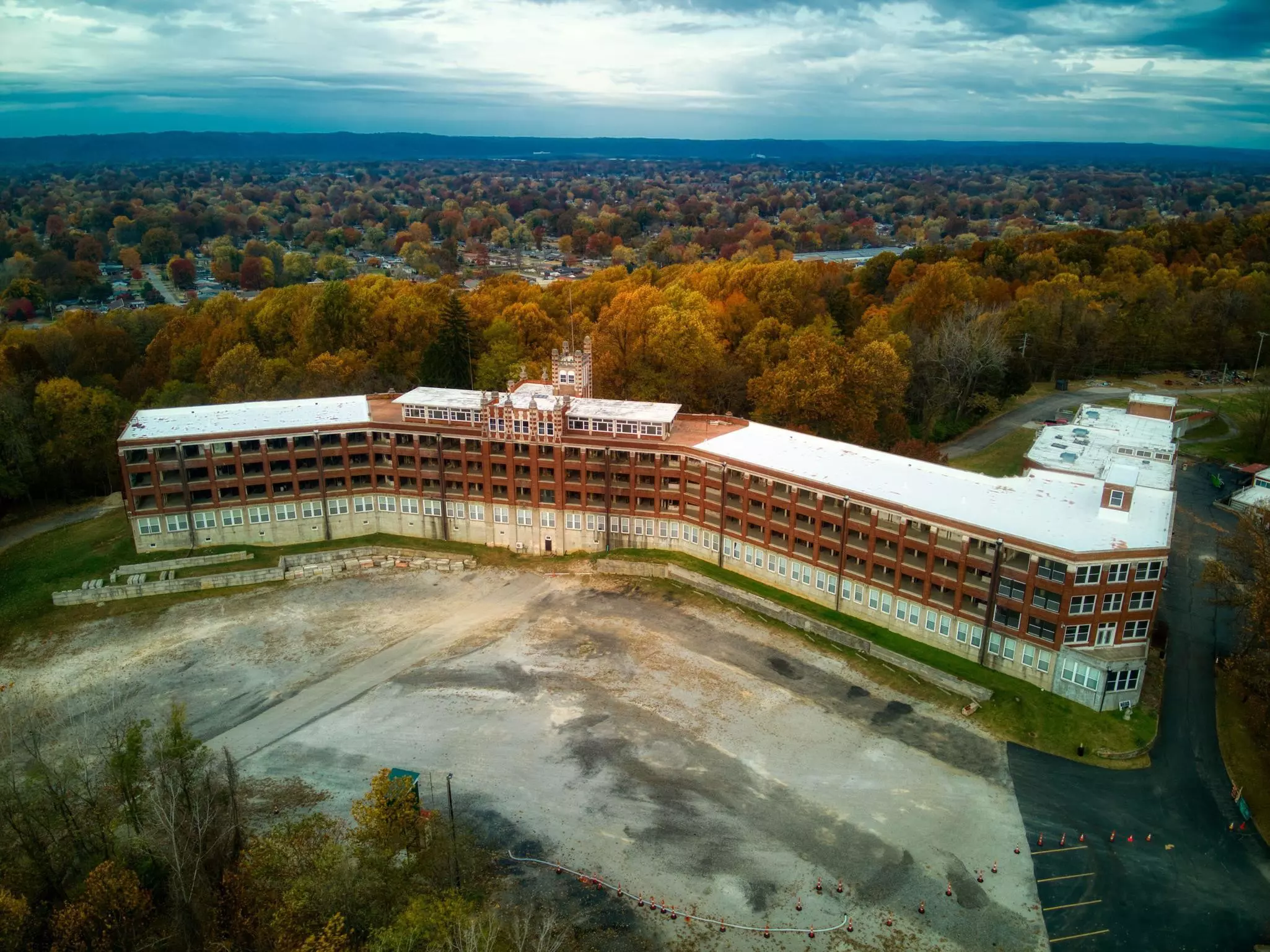 An aerial drone shot of a former sanitorium, a large brick and cement building with cement courtyard.