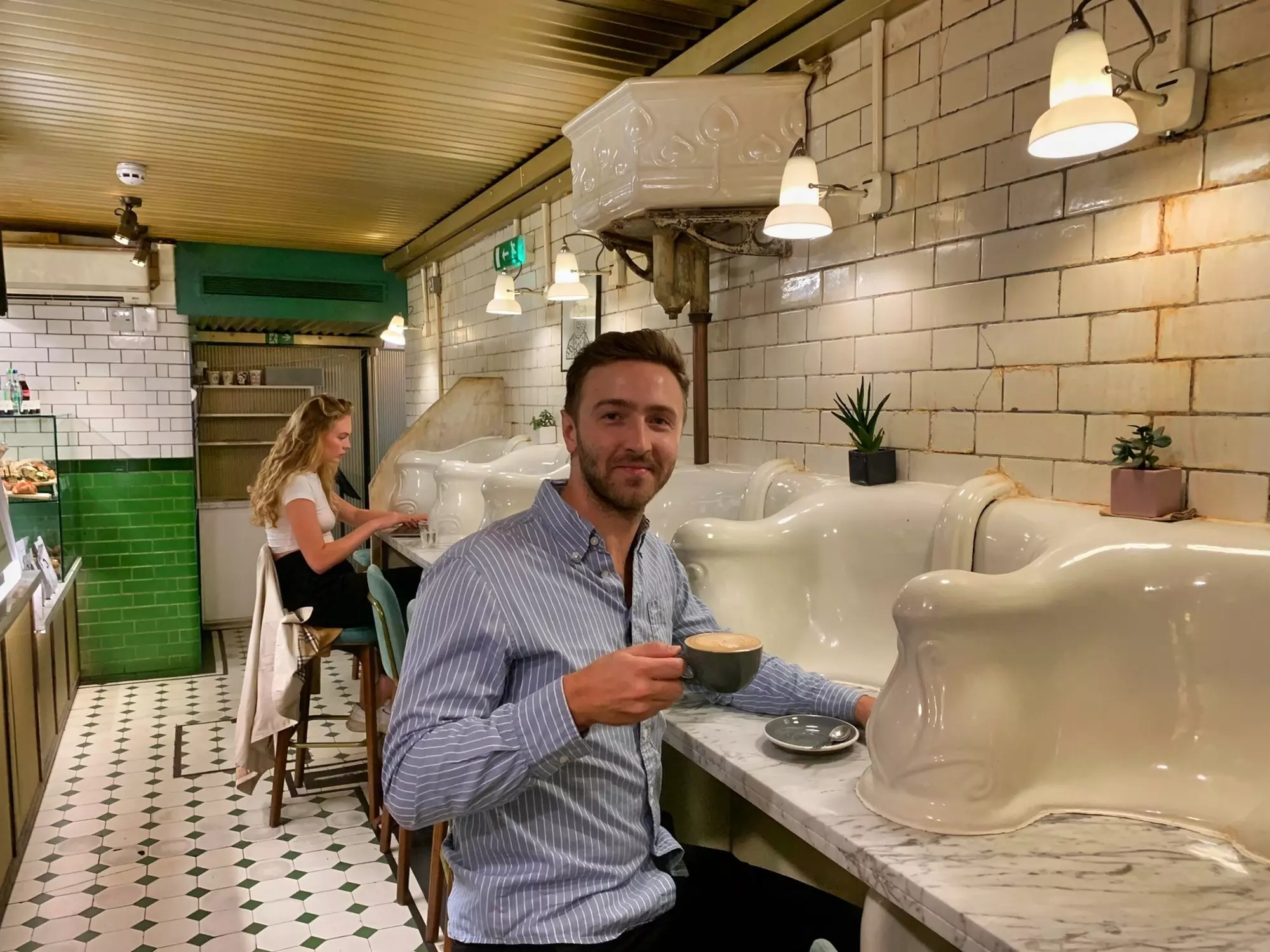 Man holding a cup of coffee in an underground Victorian coffee shop.