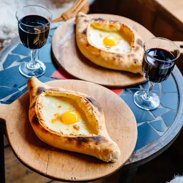 A table with Khachapuri and red wine in Tbilisi, Georgia.