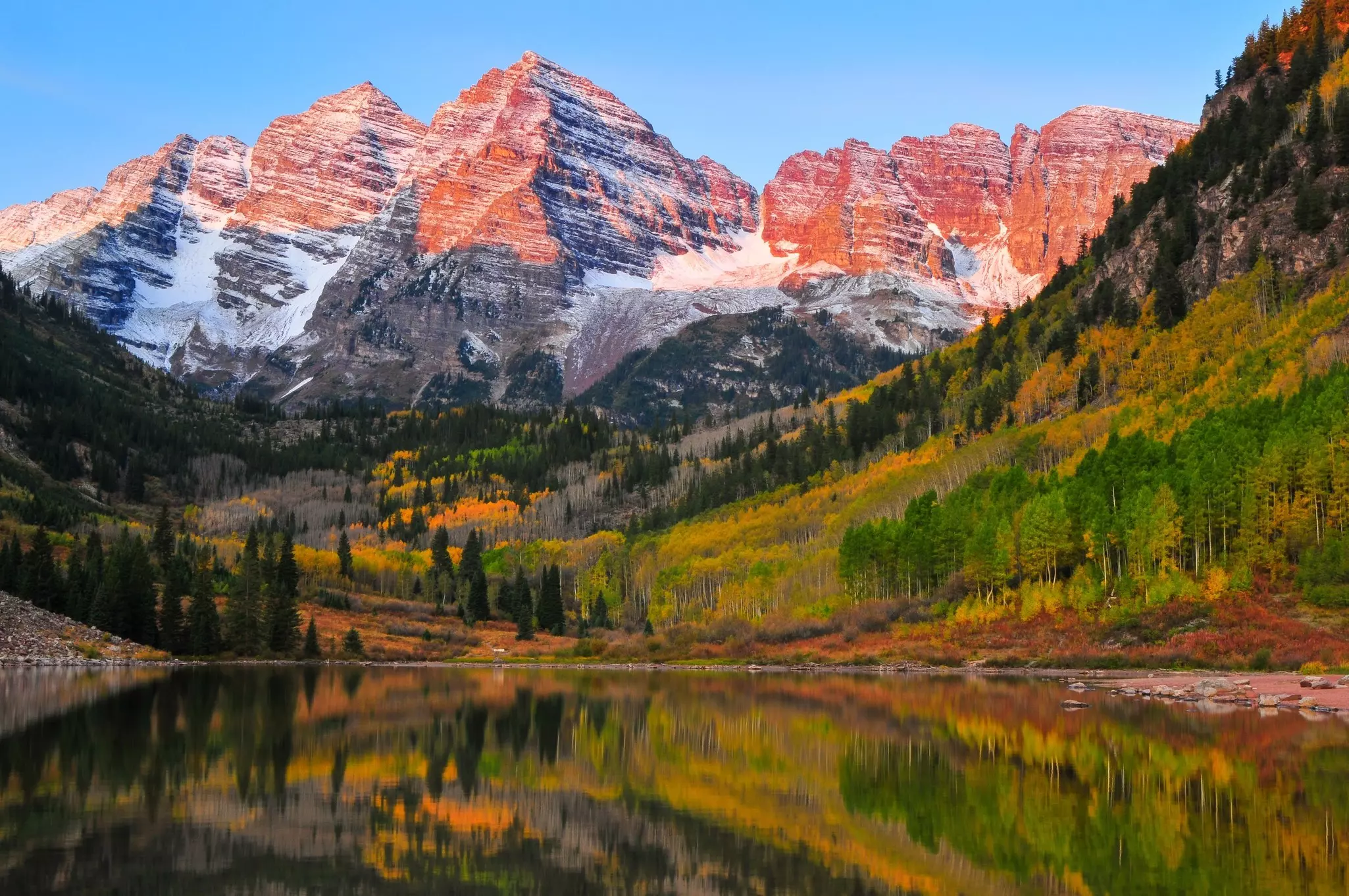 Ruddy mountains surrounded by multicolored trees reflected in a lake in Aspen, Colorado