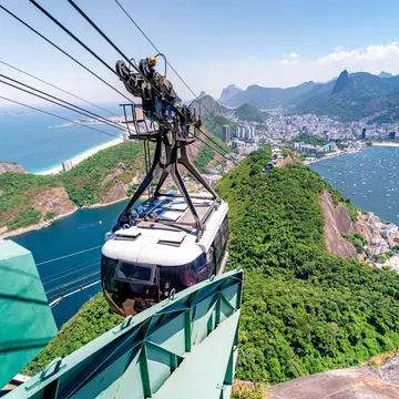View of the cable car crossing over to Sugarloaf Mountain with the city of Rio de Janeiro in the background in Brazil.