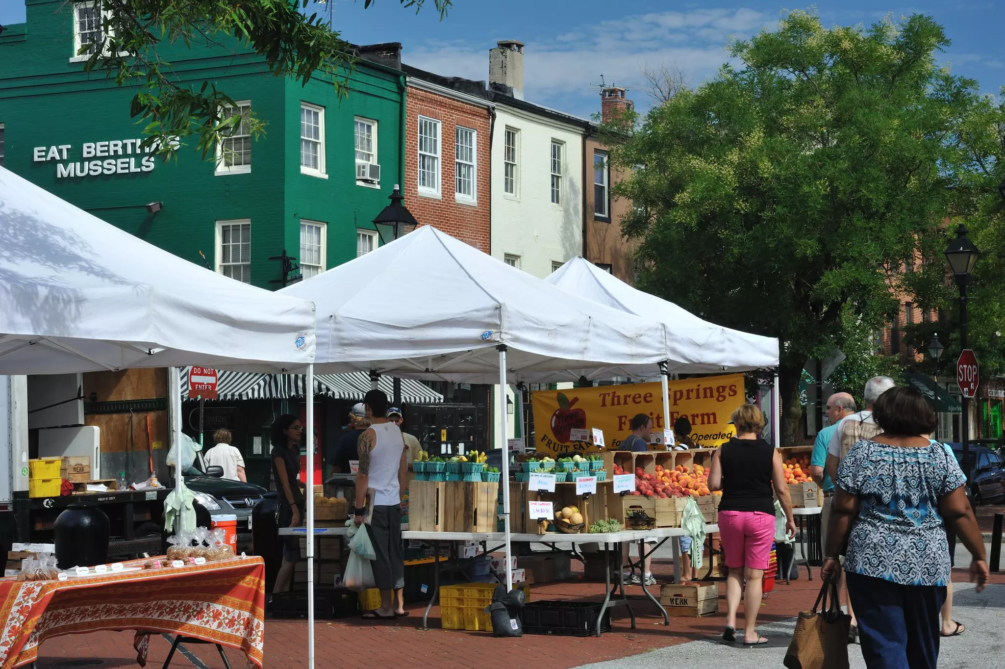 People shop at an outdoor waterfront farmer's market in Baltimore