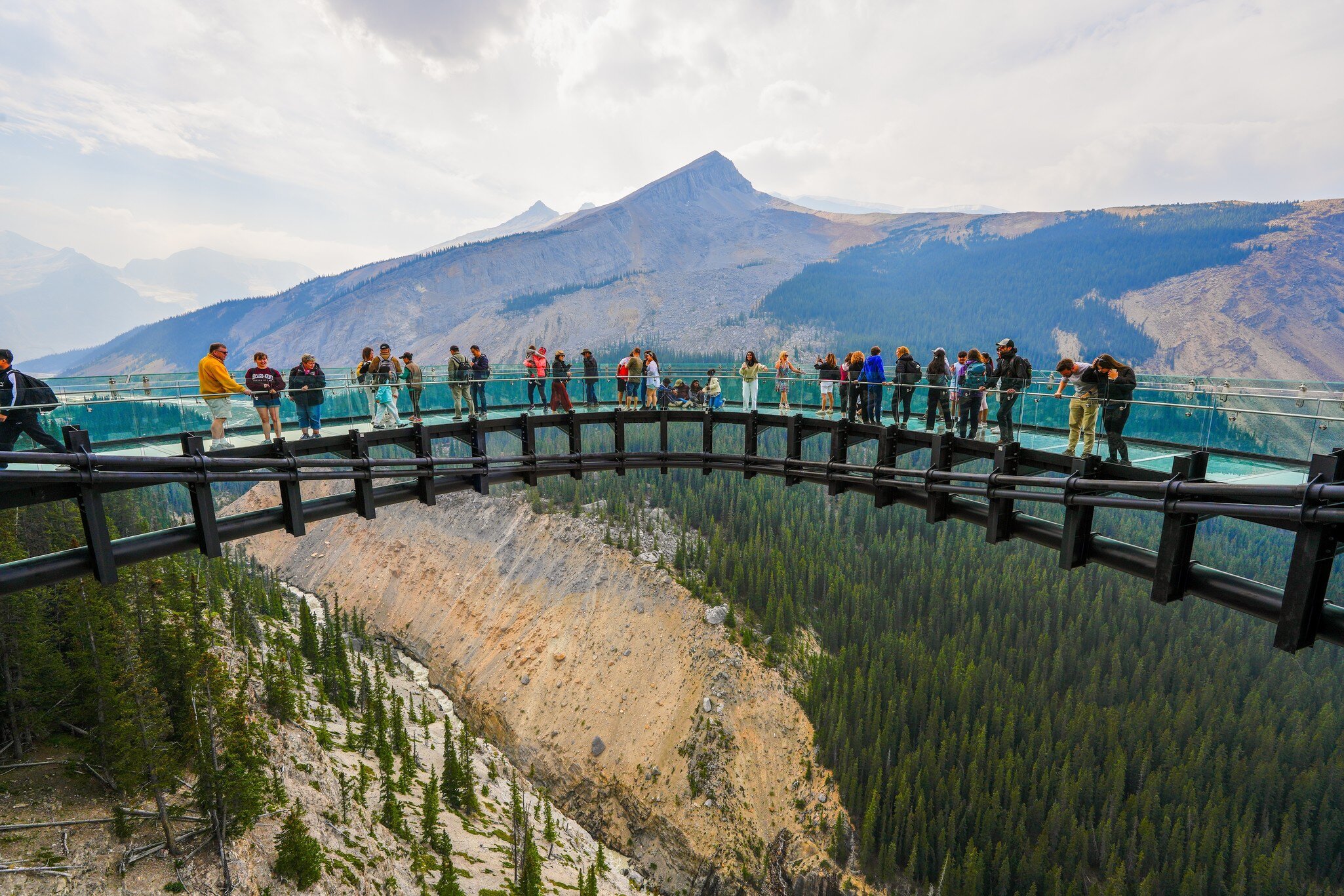 Visitors standing on the Columbia Icefield Skywalk, a cliffside walkway with glass-floor suspended above the Sunwapta Valley along the Icefields Parkway in Jasper National Park, Canada.