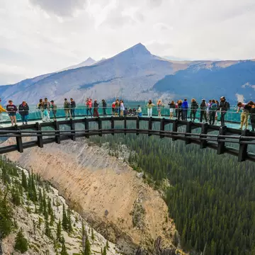 Visitors standing on the Columbia Icefield Skywalk, a cliffside walkway with glass-floor suspended above the Sunwapta Valley along the Icefields Parkway in Jasper National Park, Canada.
