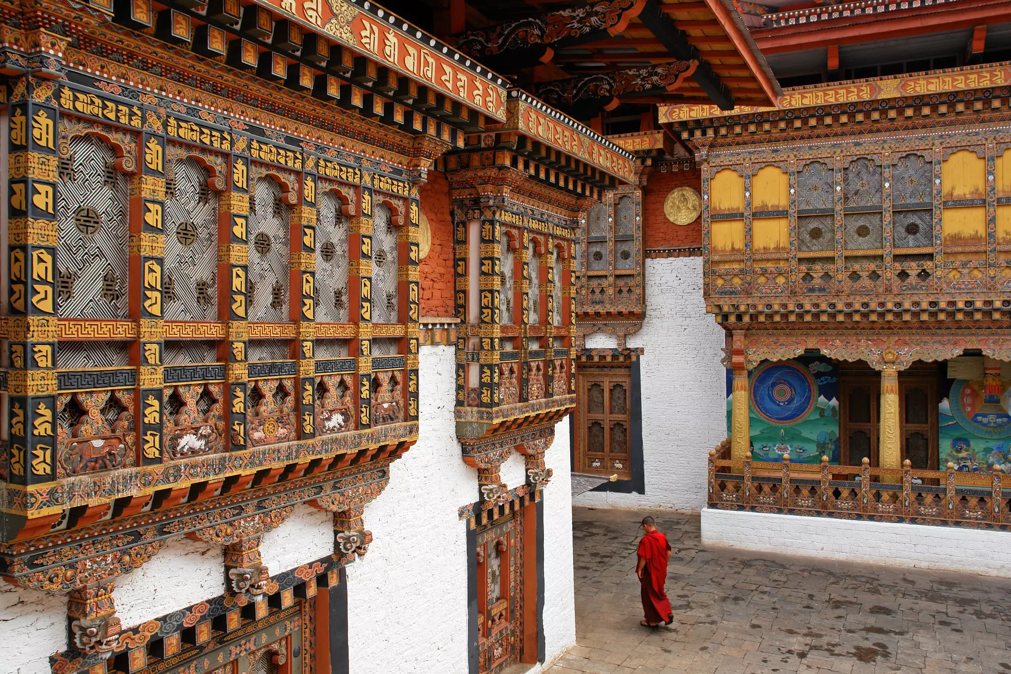 A monk walks among ornate carvings in a Punakha Temple.