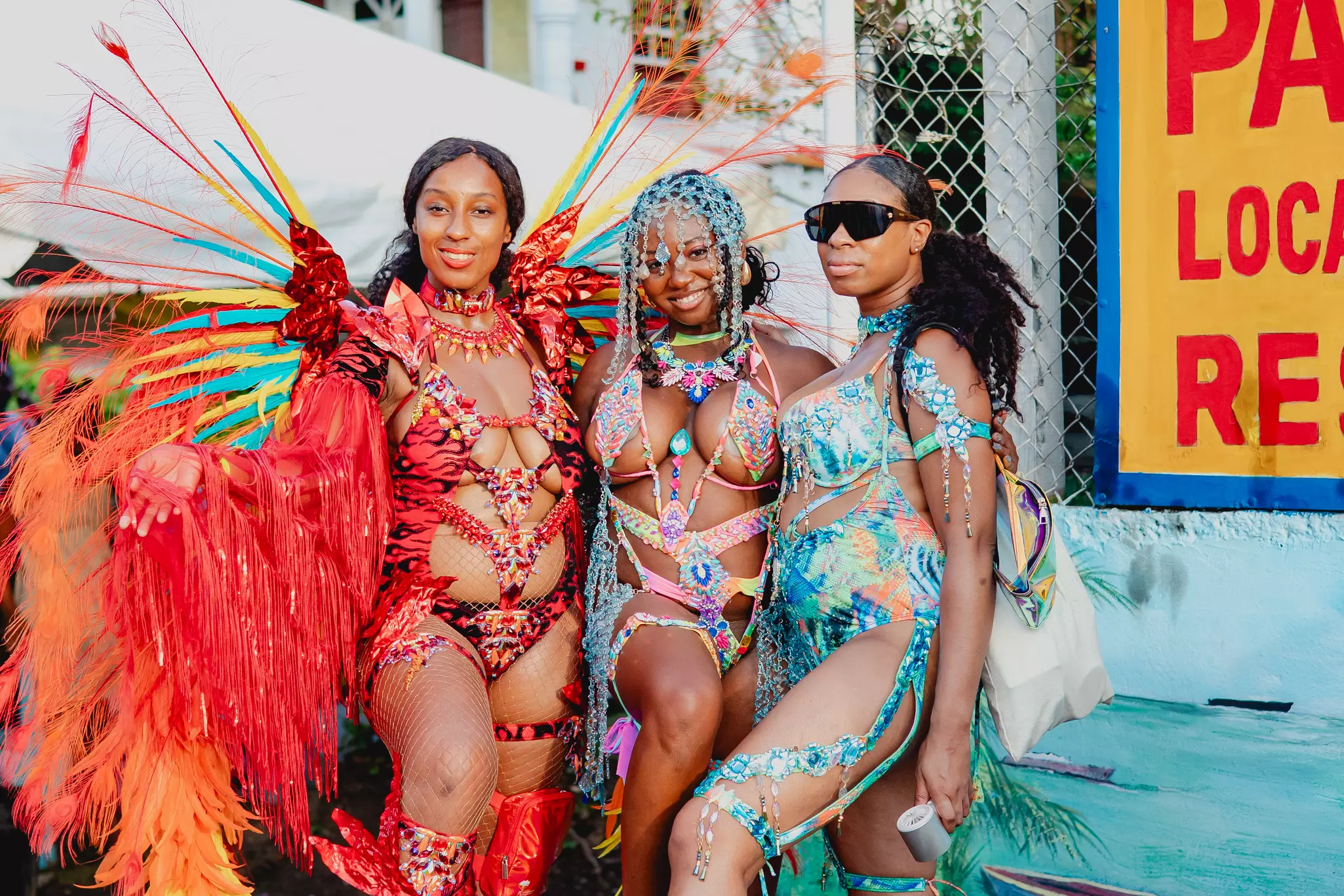A group of women dressed in colorful carnival costumes pose on the road for pictures during Spicemas in Grenada.