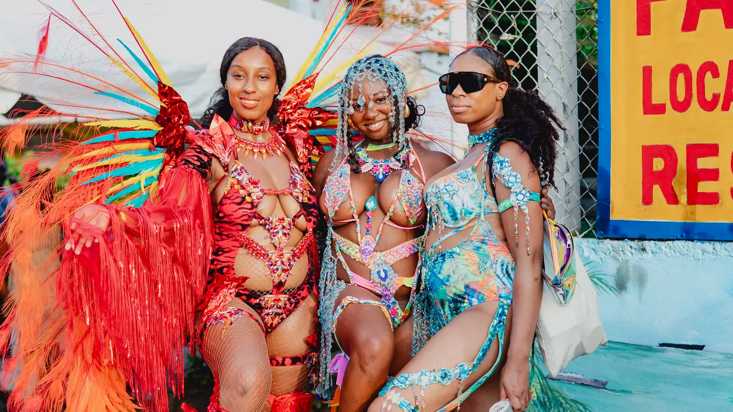 A group of women dressed in colorful carnival costumes pose on the road for pictures during Spicemas in Grenada.