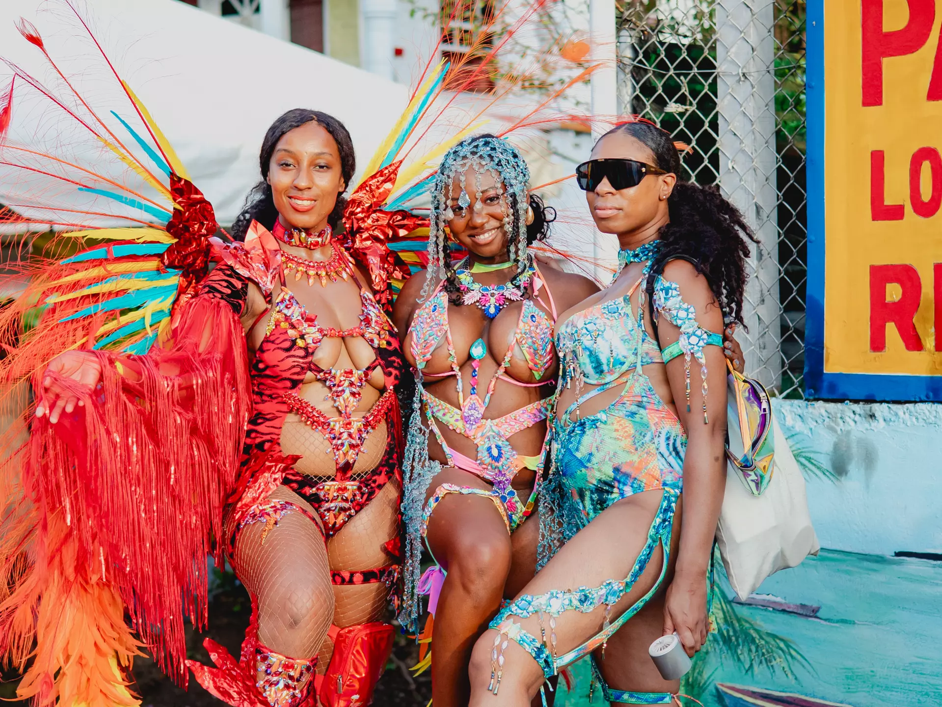 A group of women dressed in colorful carnival costumes pose on the road for pictures during Spicemas in Grenada.