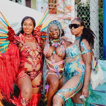A group of women dressed in colorful carnival costumes pose on the road for pictures during Spicemas in Grenada.