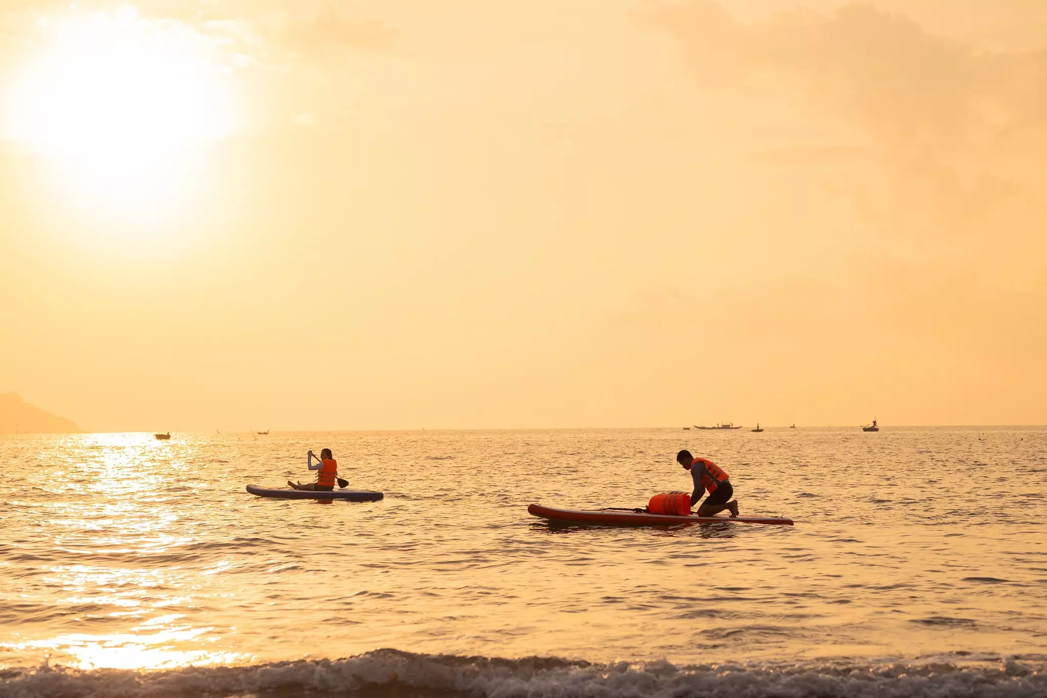 Two paddleboarders in a golden sunset.