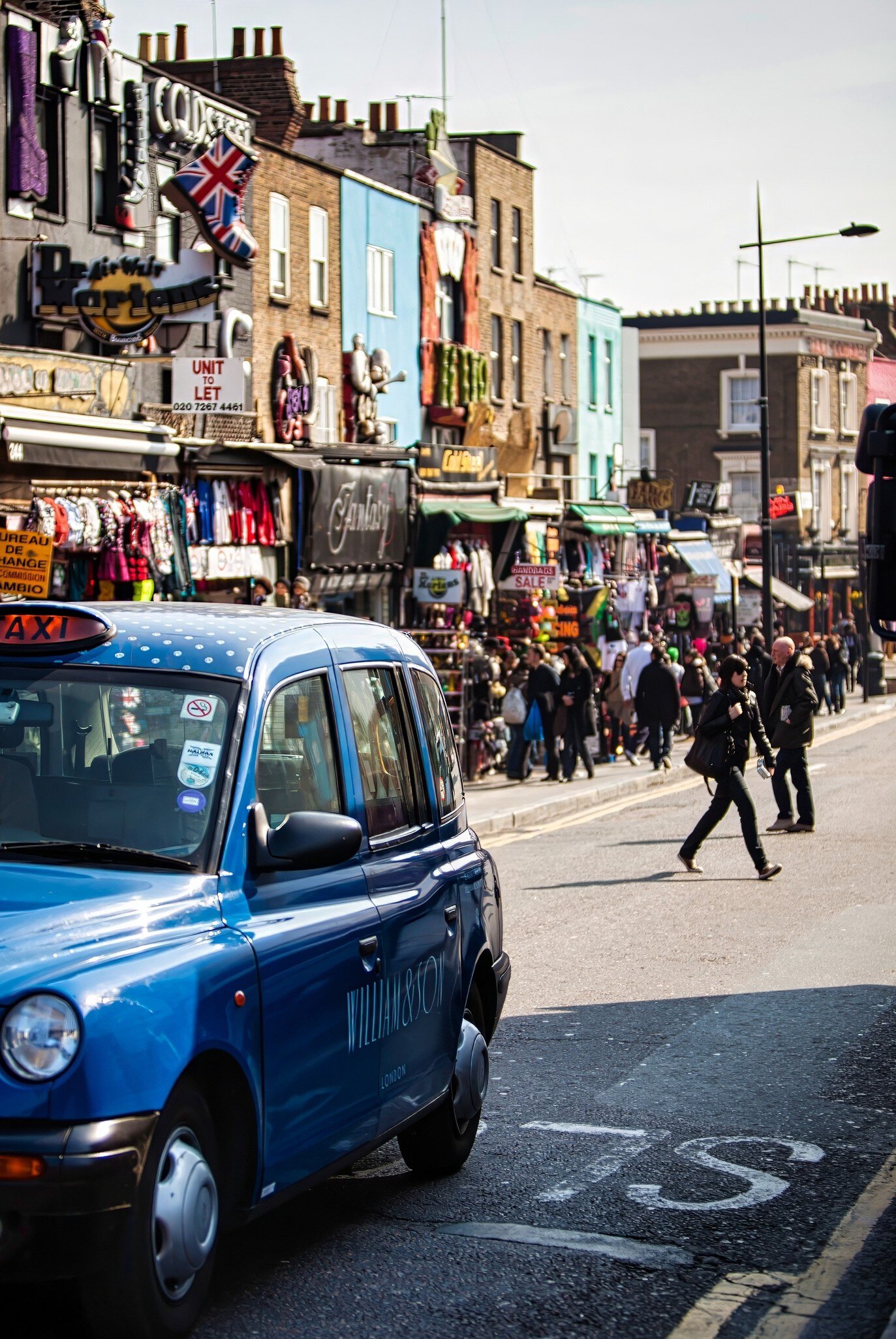 London, United Kingdom - March 20 2009 : Visitors stroll through Camden Market while a blue taxi passes on the street under a clear sky in London United Kingdom., License Type: media, Download Time: 2025-07-28T19:57:13.000Z, User: katelyn.perry_lonelyplanet, Editorial: true, purchase_order: 65050 - Digital Destinations and Articles, job: wip, client: wip, other: Katelyn Perry