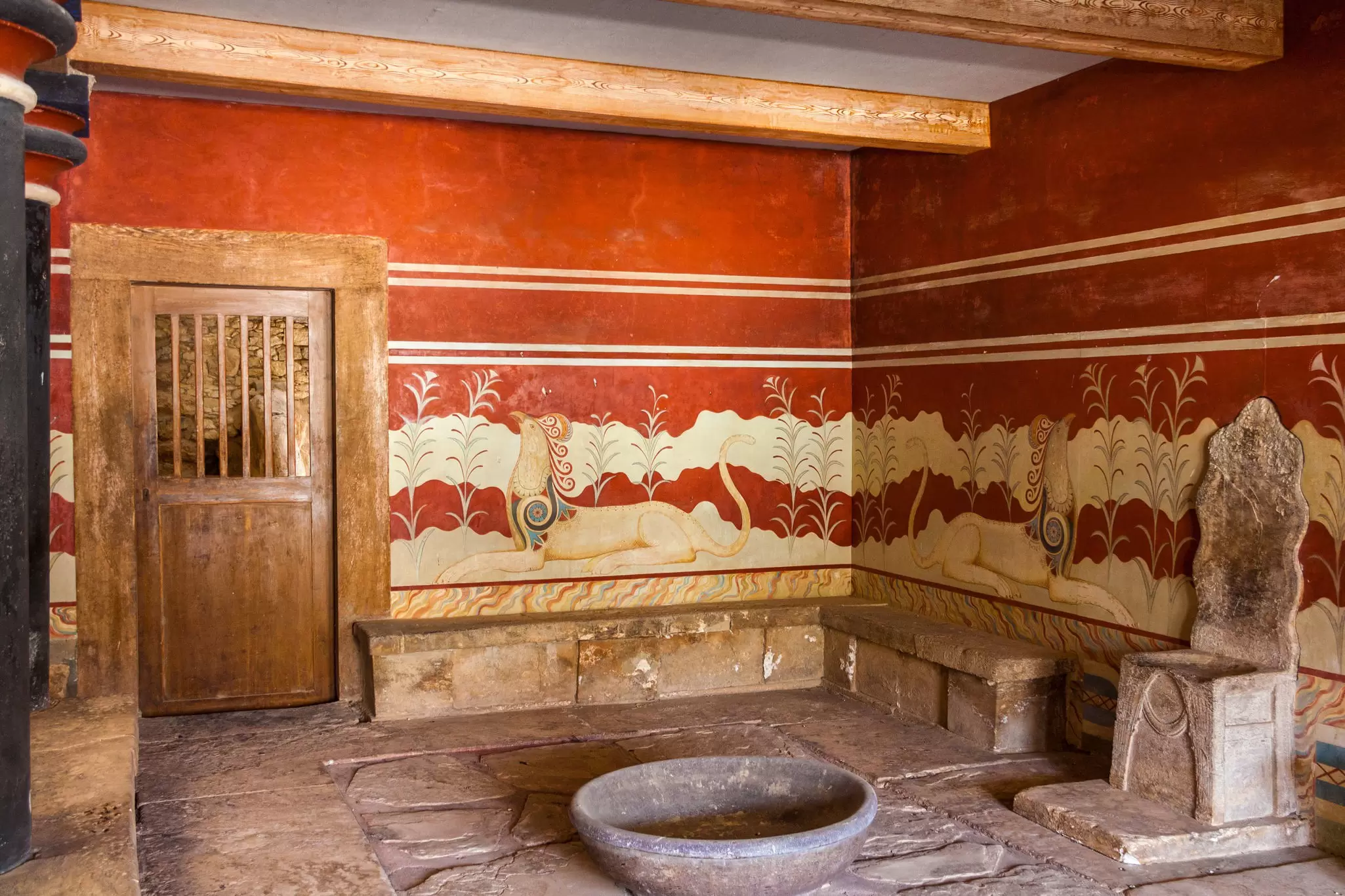 King's chamber of legendary Knossos palace, Crete, Greece. The room is large with red walls and a throne-like chair in the centre of it.