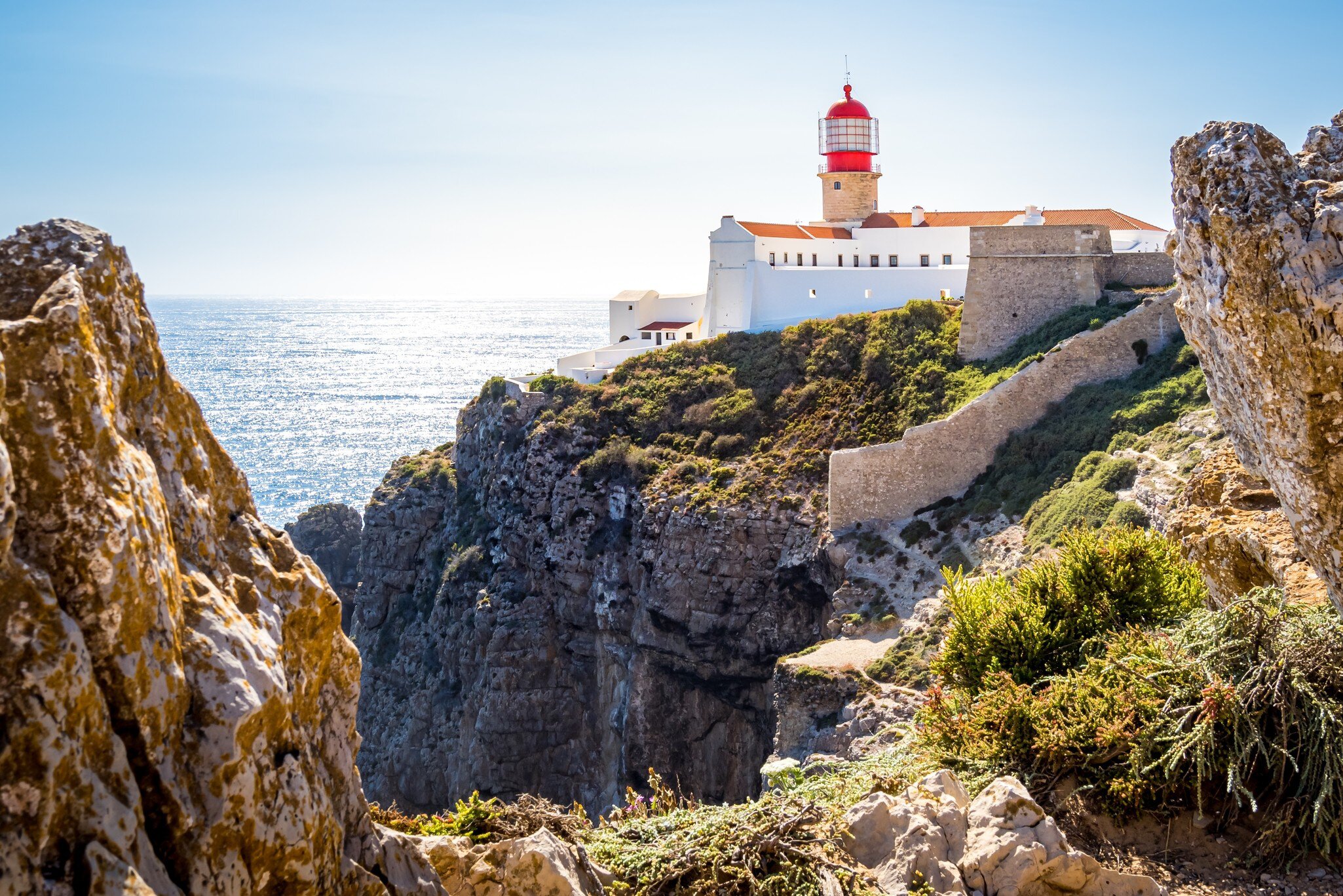 View of the lighthouse on top of the rugged cliffs of Cabo de São Vicente, with the Atlantic Ocean in the background in Portugal.