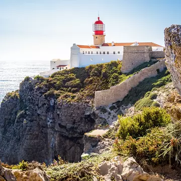 View of the lighthouse on top of the rugged cliffs of Cabo de São Vicente, with the Atlantic Ocean in the background in Portugal.