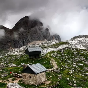 Rain clouds over Triglav Lakes Valley, Prehodavci pass, with winter room and shelter of a hut on the mountain.
