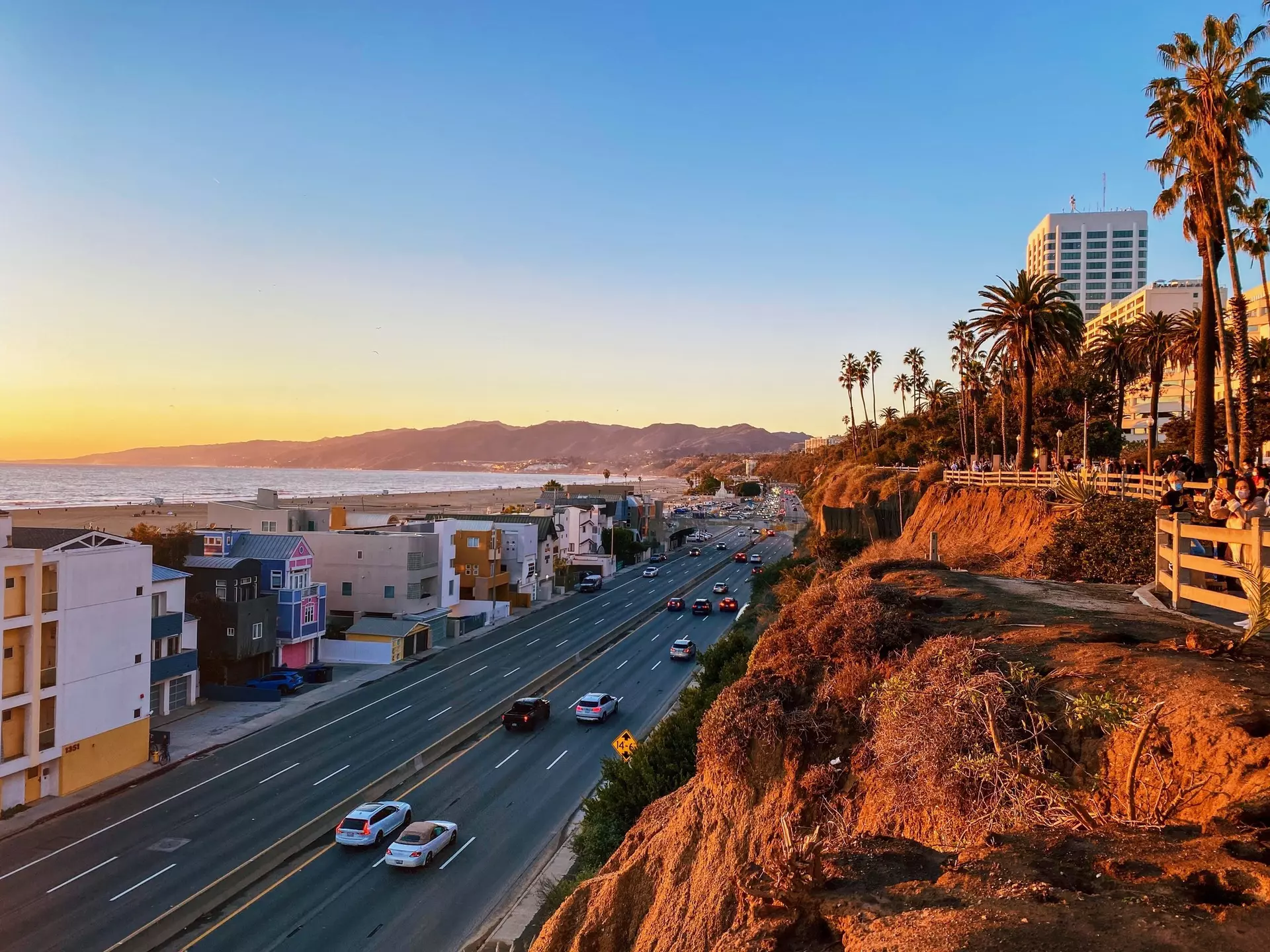 Cars on the Pacific Coast Highway in Santa Monica, with the cliffs lit up at sunset, Los Angeles, California, USA.