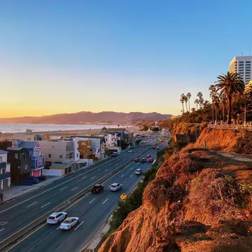 Cars on the Pacific Coast Highway in Santa Monica, with the cliffs lit up at sunset, Los Angeles, California, USA.