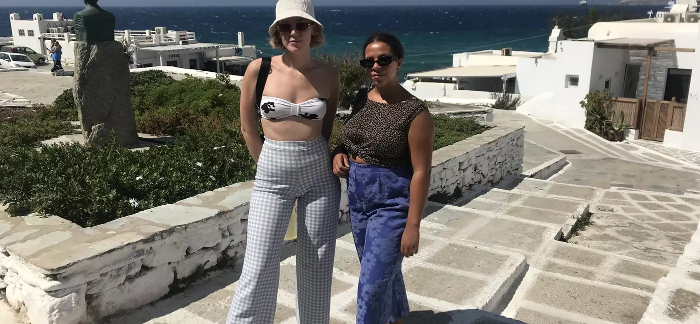 Two women pose for a photo on a stone pathway near the sea