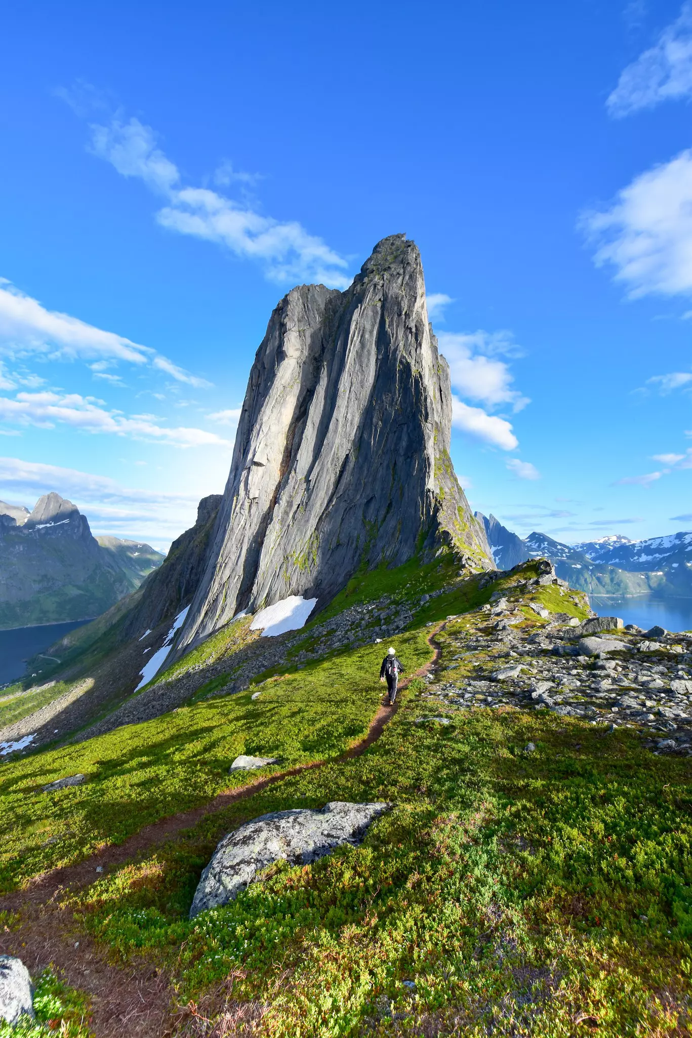 A relatively narrow mountain peak juts into a blue sky