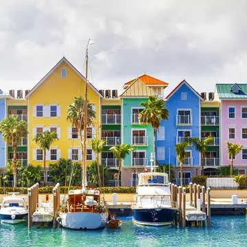 A row of pastel-painted houses on the shore with boats docked nearby at a small harbor.