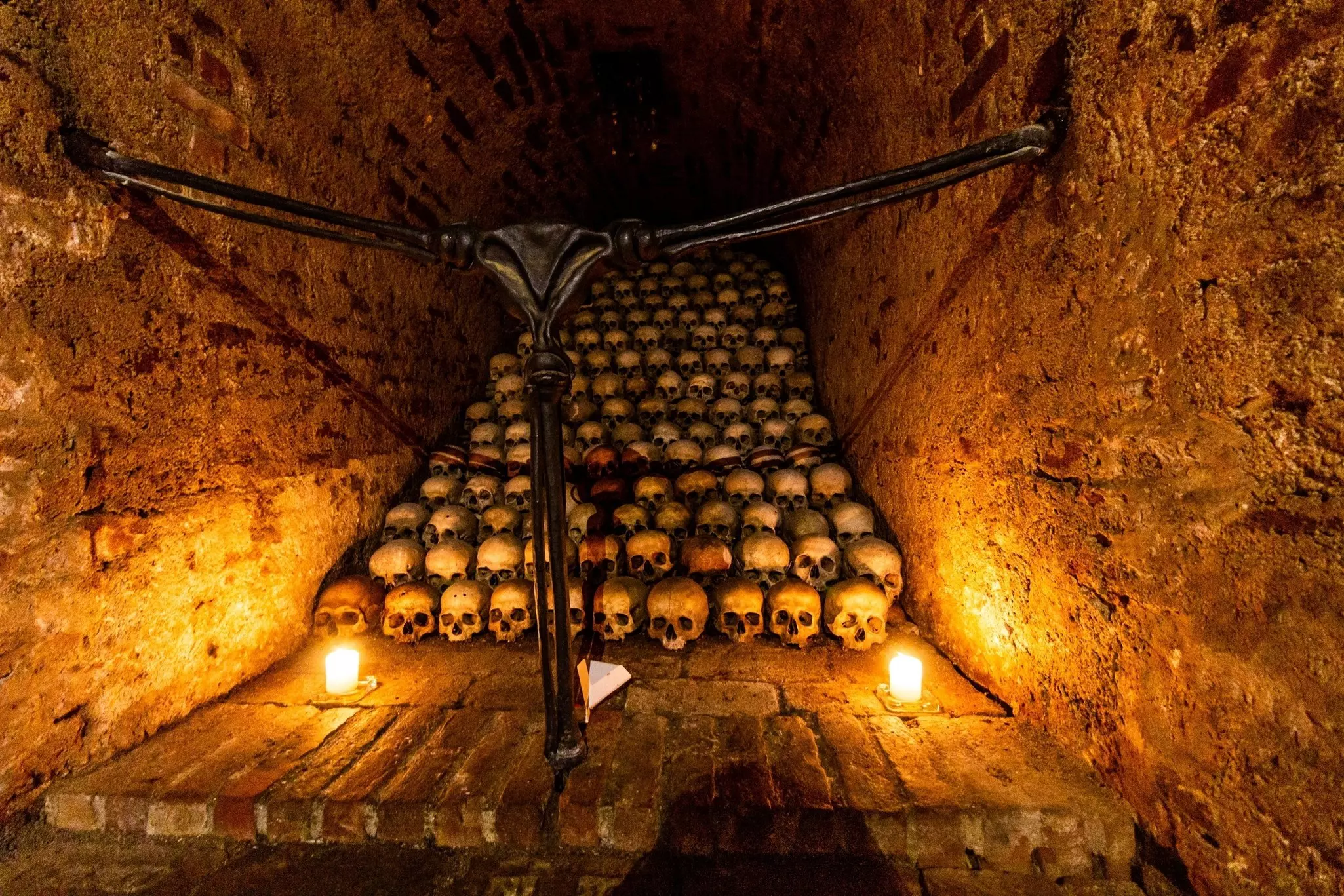 Rows of skulls are lined up and lit by candles in an underground ossuary.