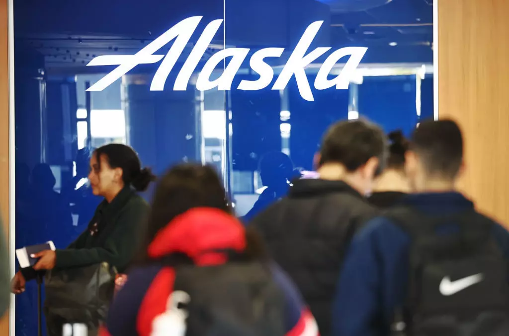 Travelers stand at an Alaska Airlines check-in area after the airline canceled its flights © Mario Tama / Staff / Getty Images