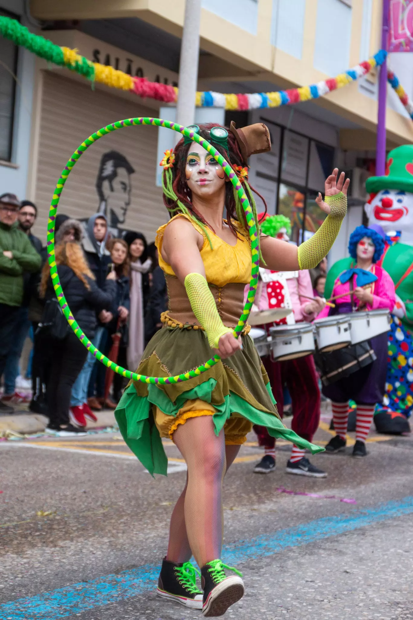 Woman dressed in yellow and green whimsical clothing and white makeup