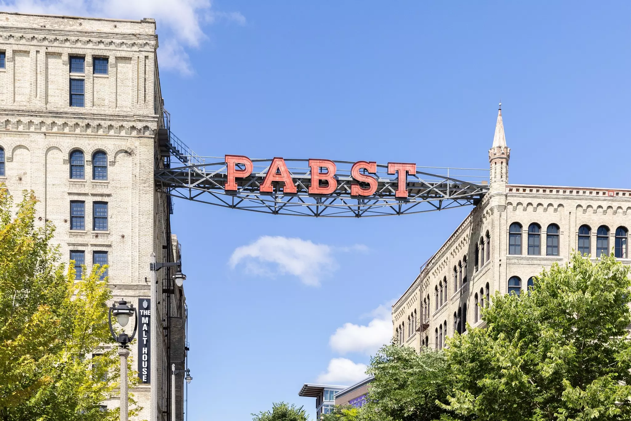White brick buildings connected by a large metal walkway and sign reading "Pabst" on a sunny day.