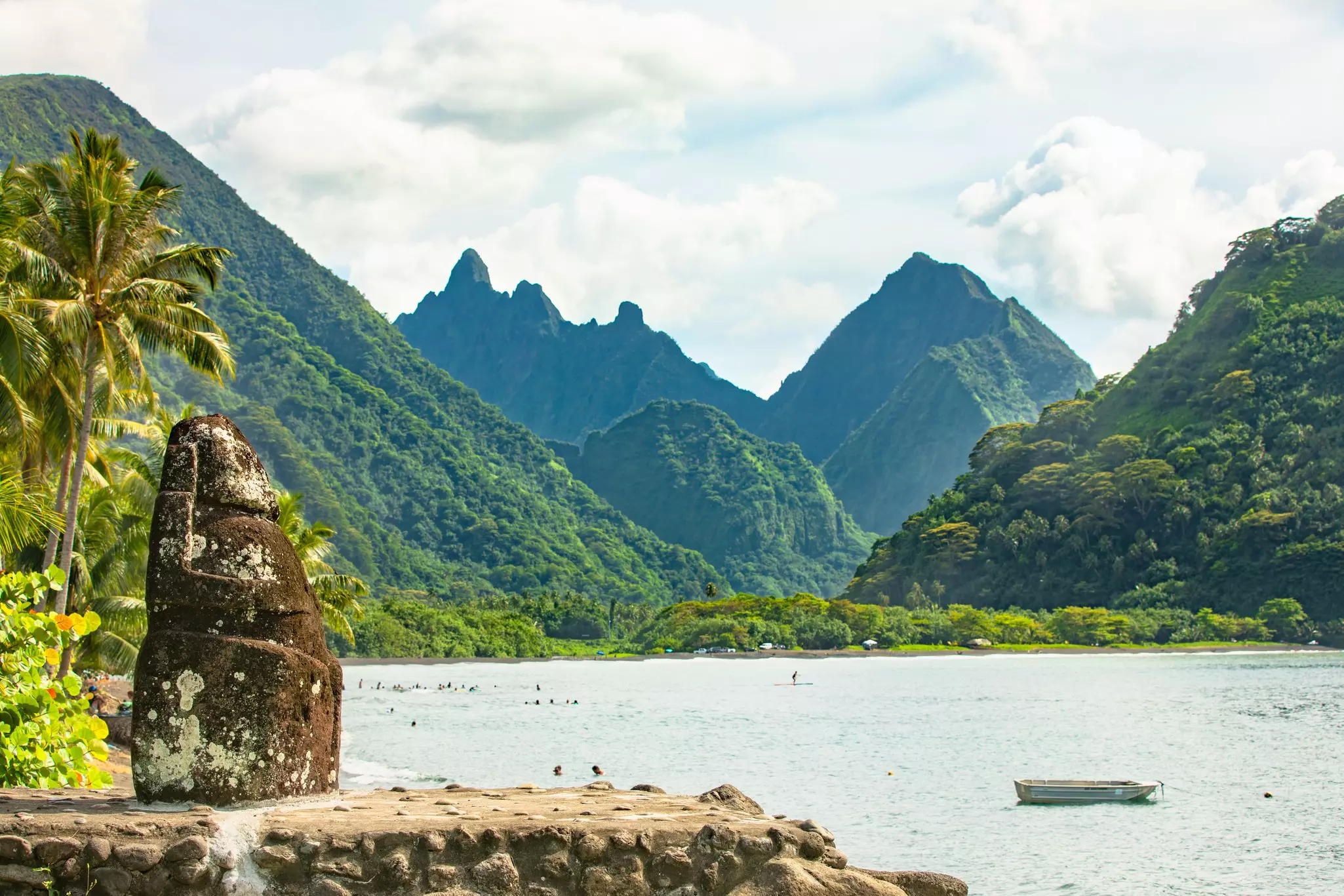Mountains rising out of the ocean with a rock creation in the foreground