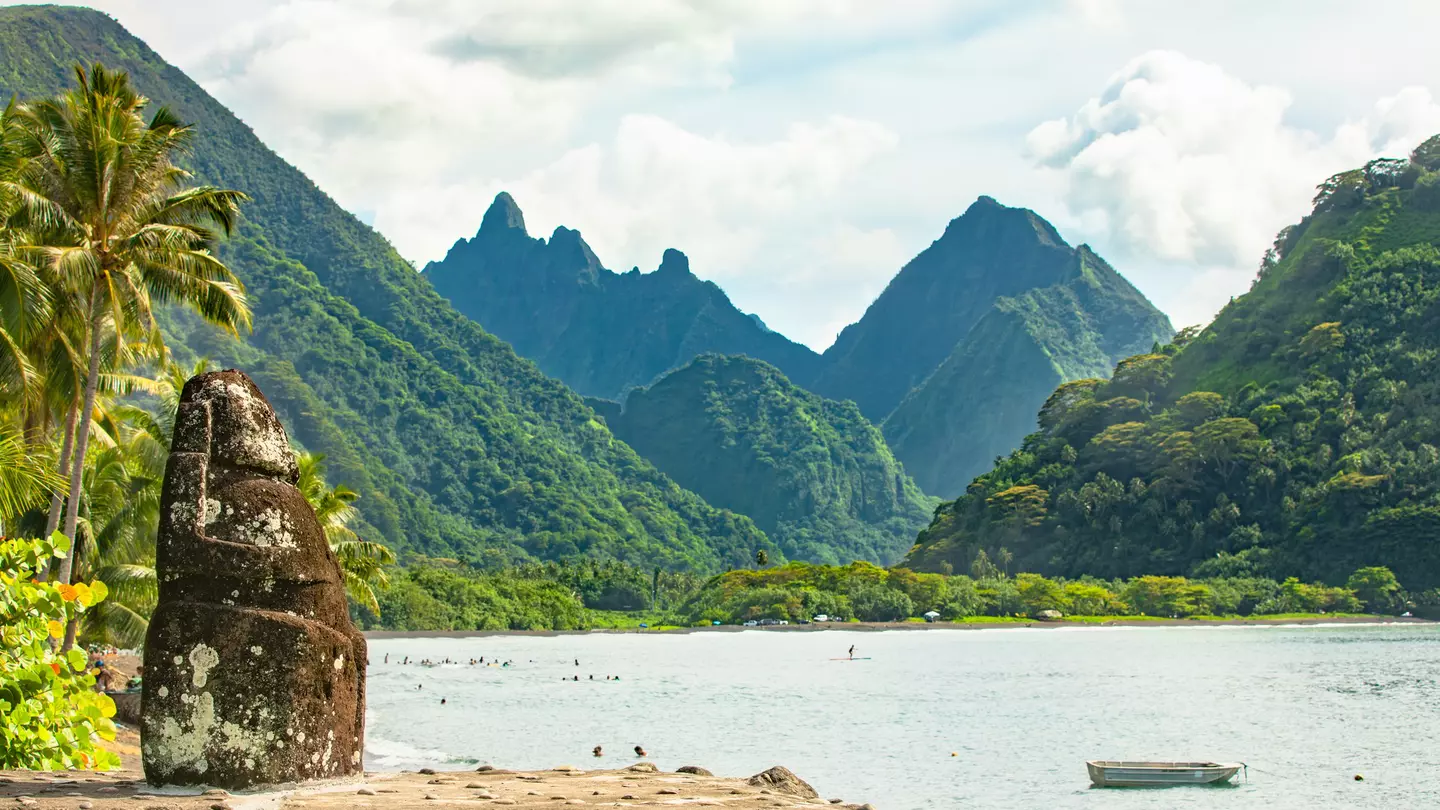 Mountains rising out of the ocean with a rock creation in the foreground