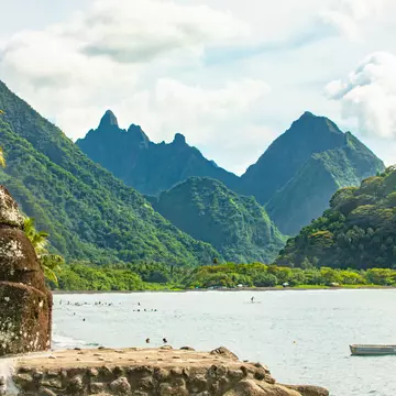 Mountains rising out of the ocean with a rock creation in the foreground