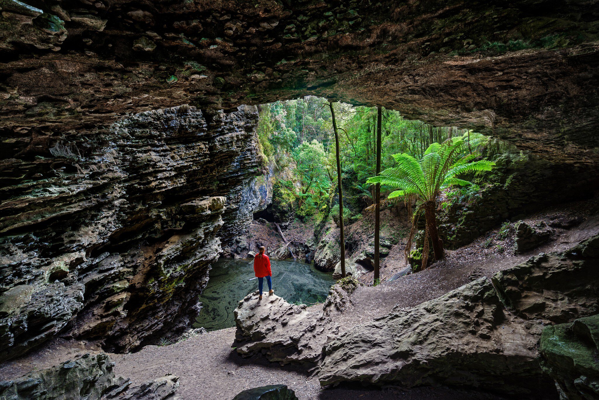 Woman standing at Trowutta Arch, Tasmania, Australia.