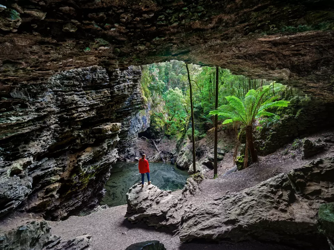 Woman standing at Trowutta Arch, Tasmania, Australia.