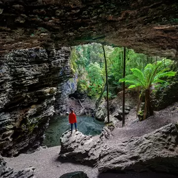 Woman standing at Trowutta Arch, Tasmania, Australia.