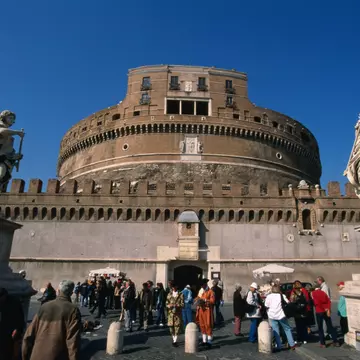 Tourists on the Pont Sant'Angelo make their way past the angels by Bernini and his pupils through to the heavily fortified Castel Sant'Angelo, Rome.