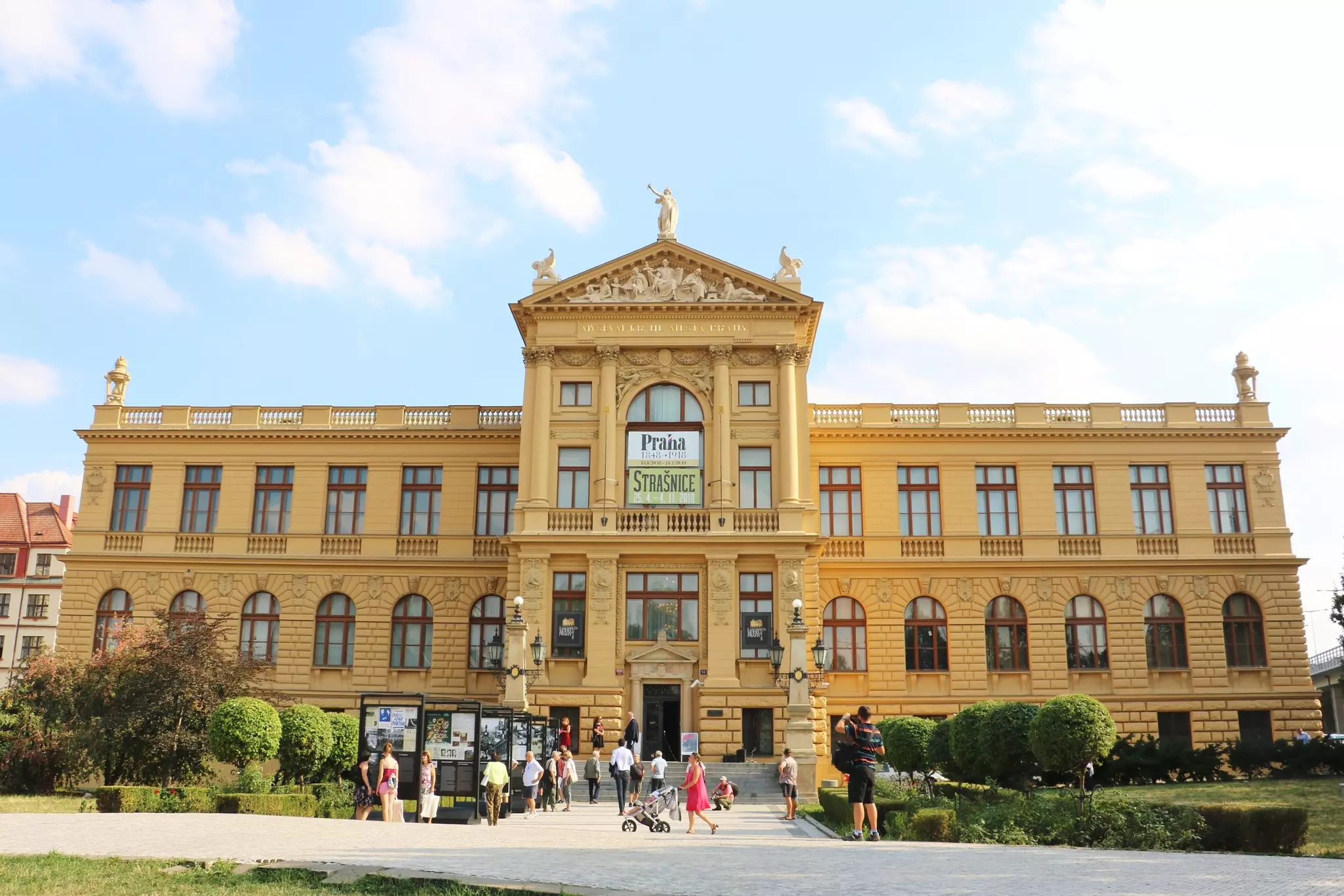 The exterior of a museum building in a city, with people looking at displys near the entrance.