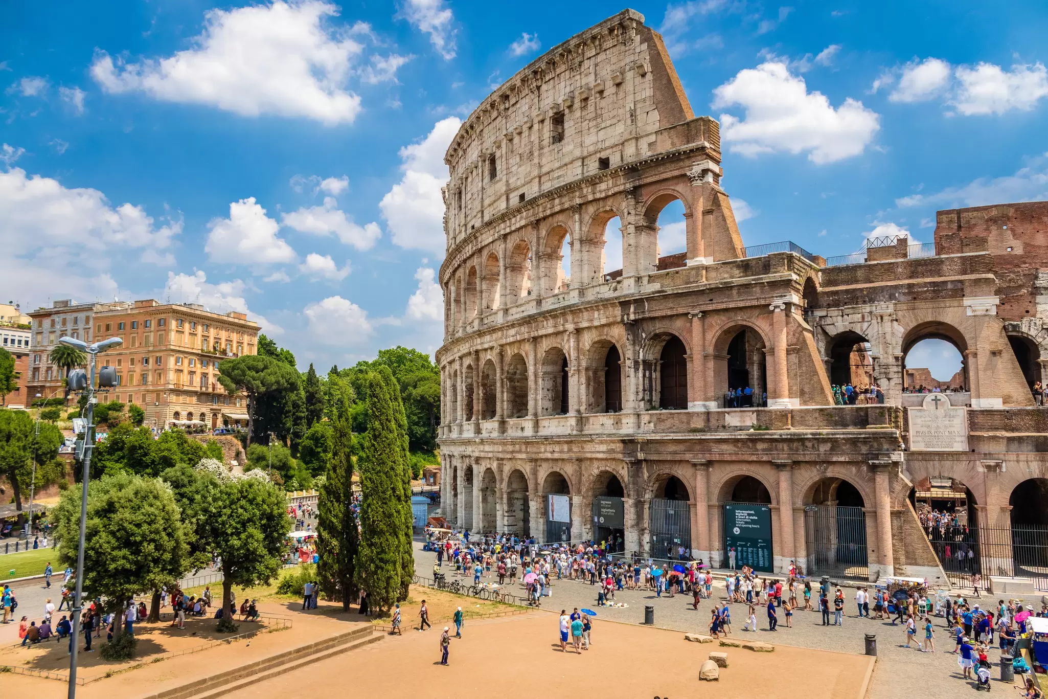 Crowd of visitors outside the Colosseum on a sunny day.