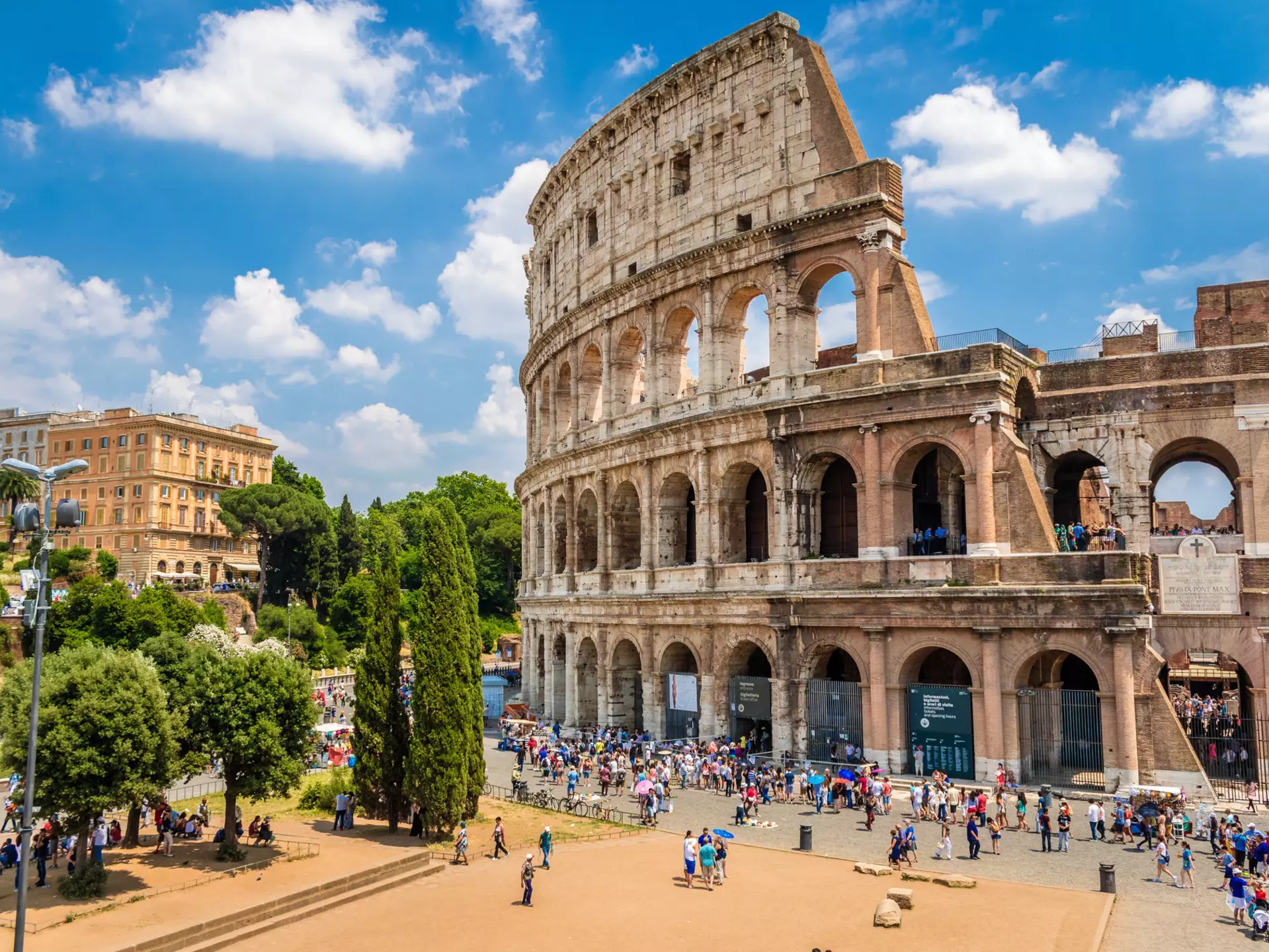 Crowd of visitors outside the Colosseum on a sunny day.