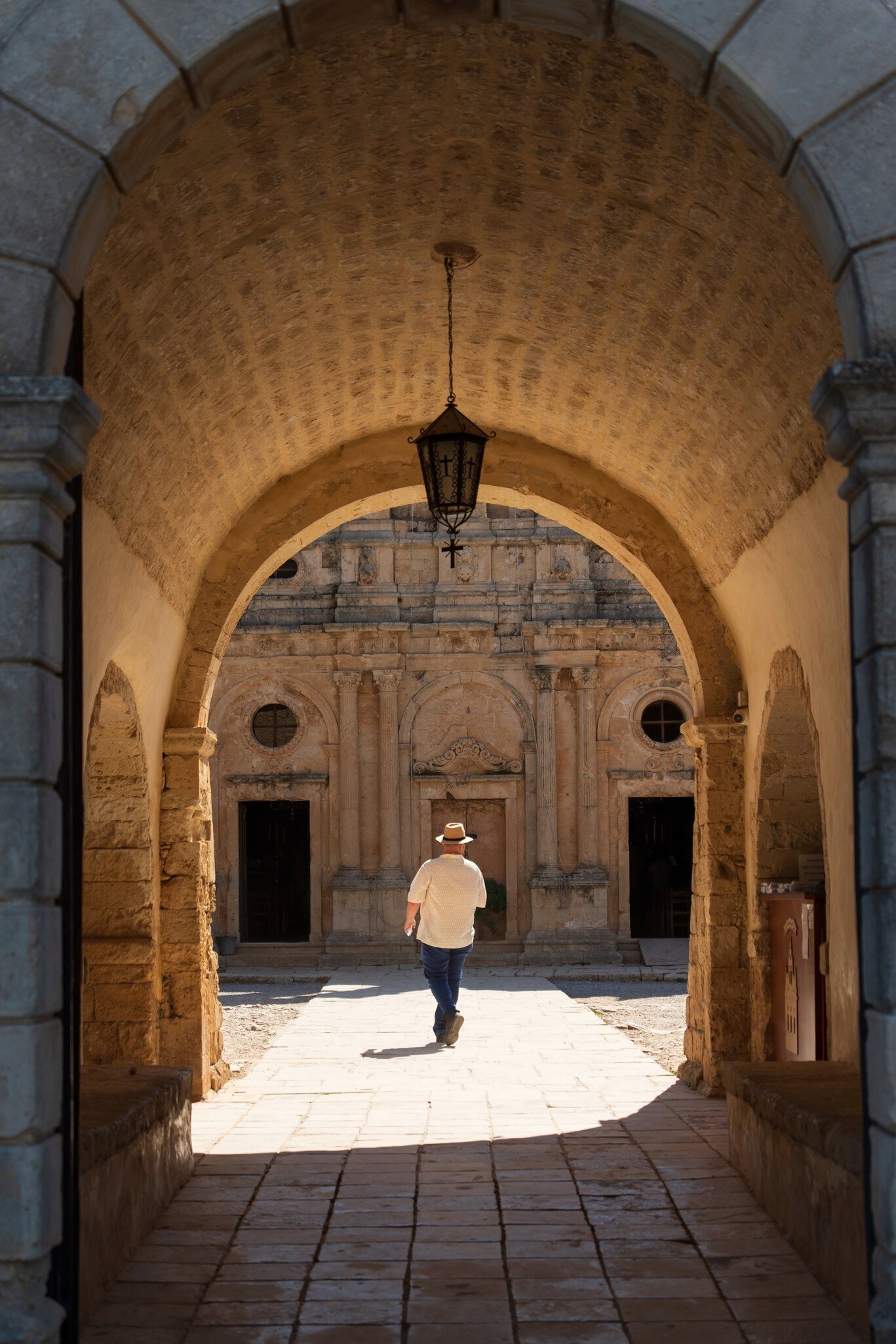 A man wearing a fedora walks into the Monastery Arkadi in Rethimno, Crete, Greece.
