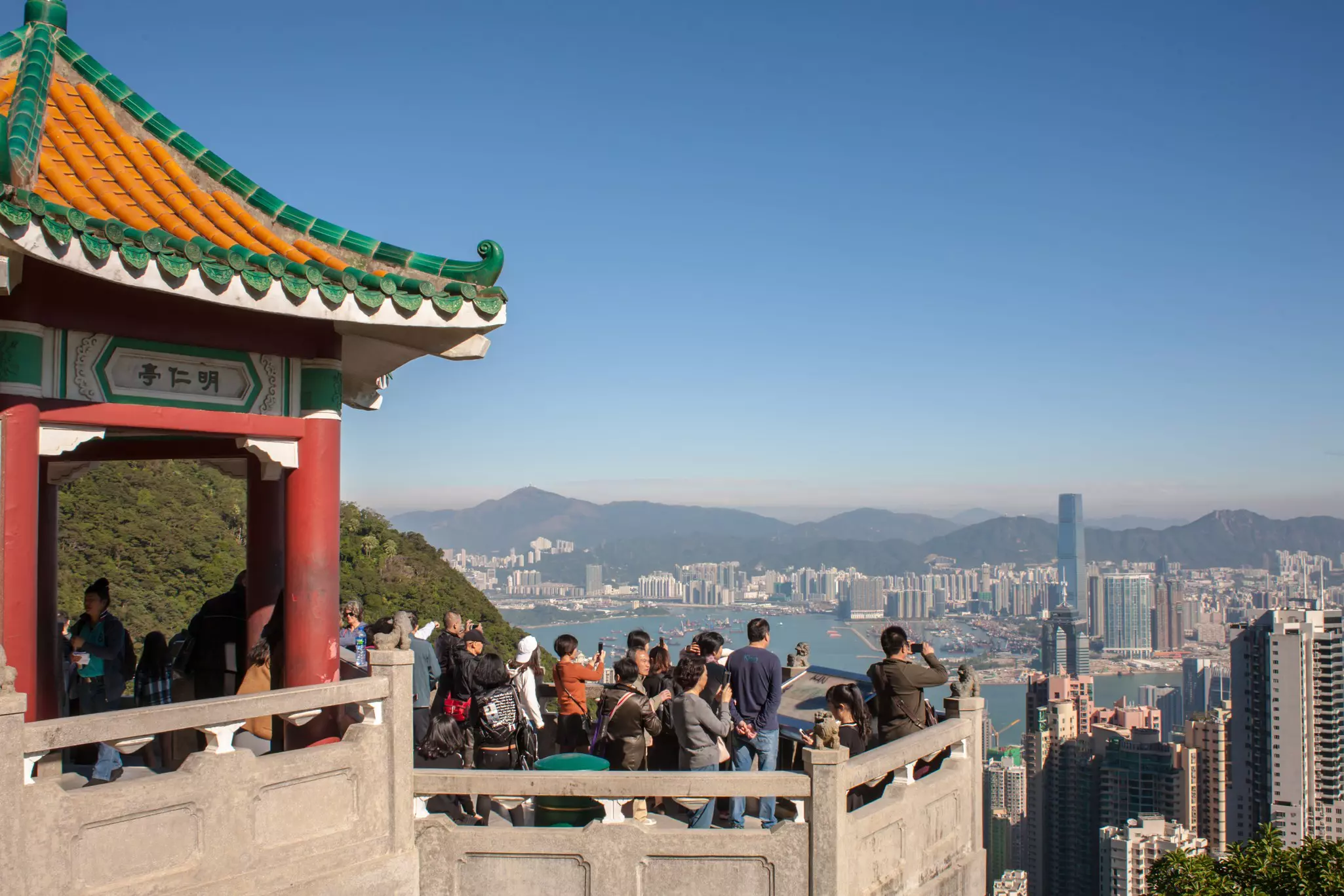 Tourists crowd at a Victoria Peak viewpoint looking out over the rooftops of Hong Kong.