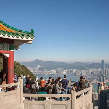 Tourists crowd at a Victoria Peak viewpoint looking out over the rooftops of Hong Kong.