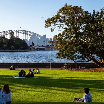 People lounging on the grass in Royal Botanic Gardens, Sydney, Australia.