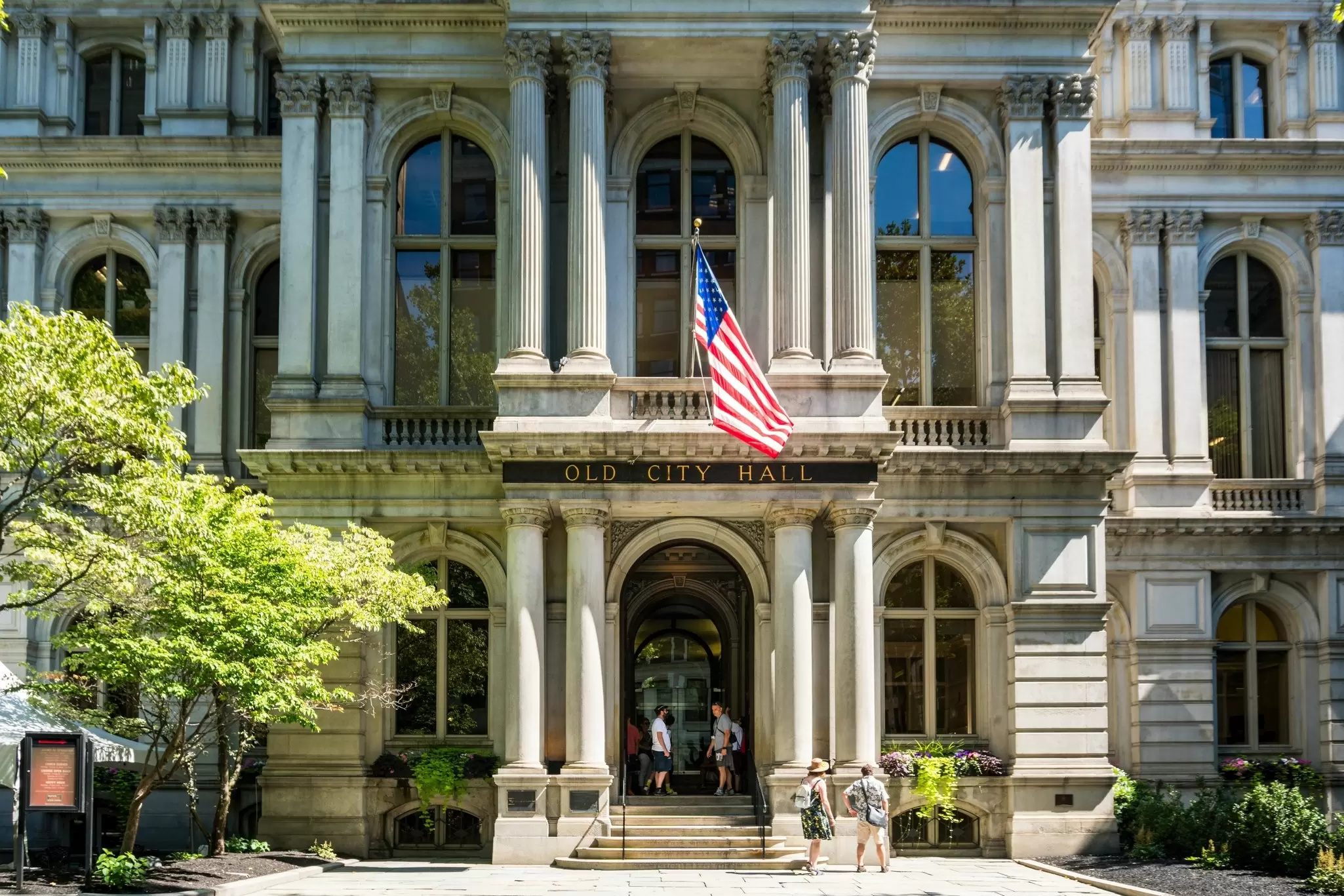 A white building with columns and an American flag; the sign above the doorway reads "Old City Hall."