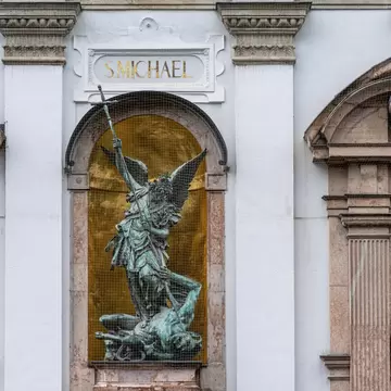 A bronze statue of Saint Michael slaying the dragon on the facade of St. Michael's Church in Munich, Germany.