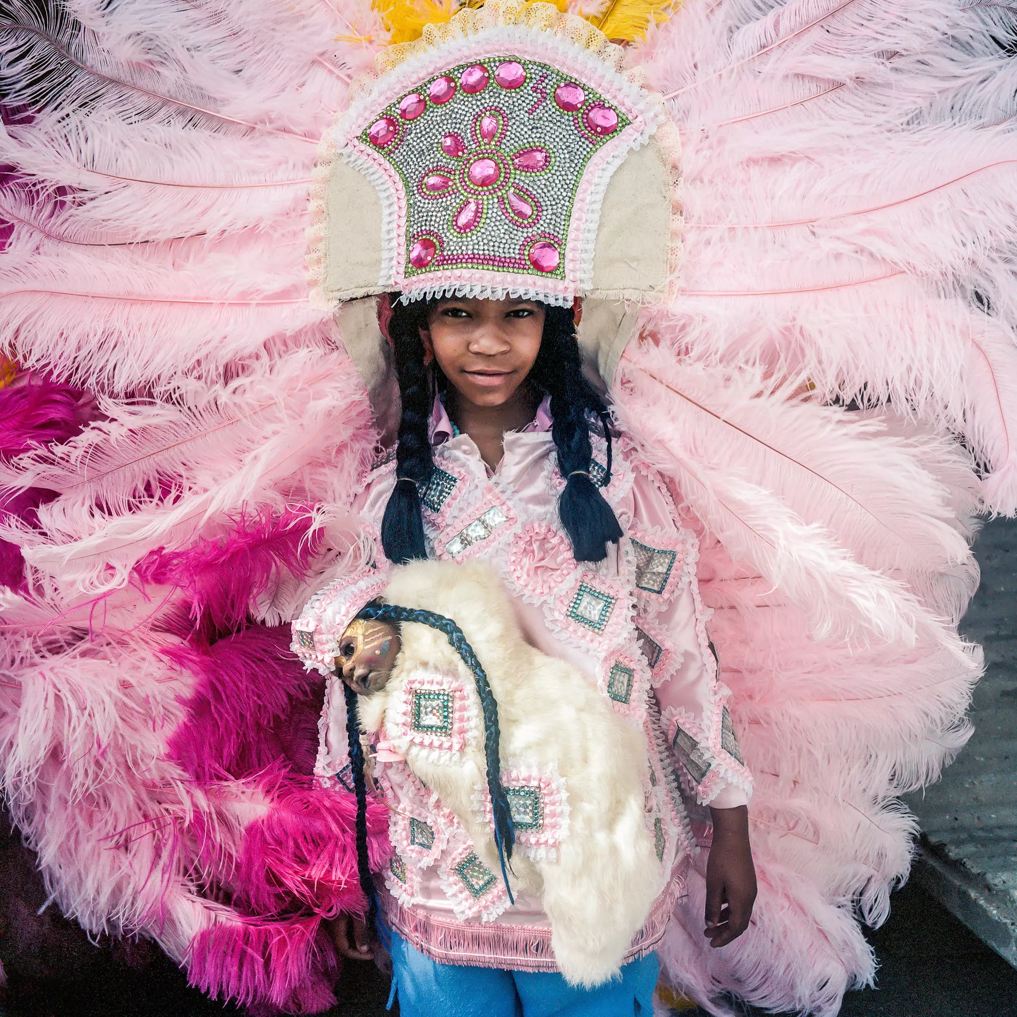 A person wears a costume with a massive pink feathered headdress.