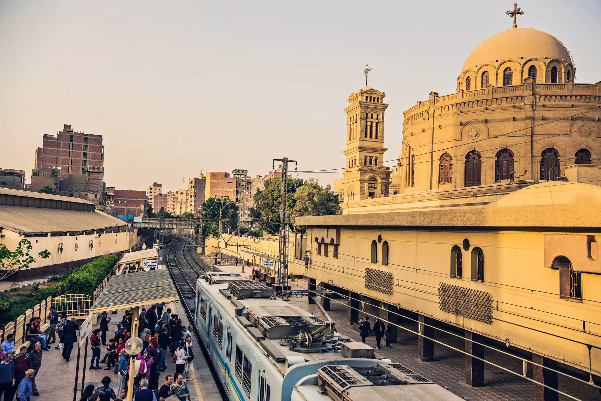 A metro train pulls into a station near a large church