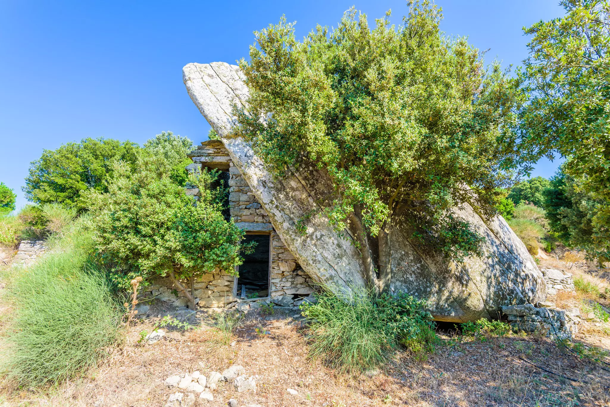 Ancient traditional stone house ruin built under a boulder on Ikaria Island, Greece. 