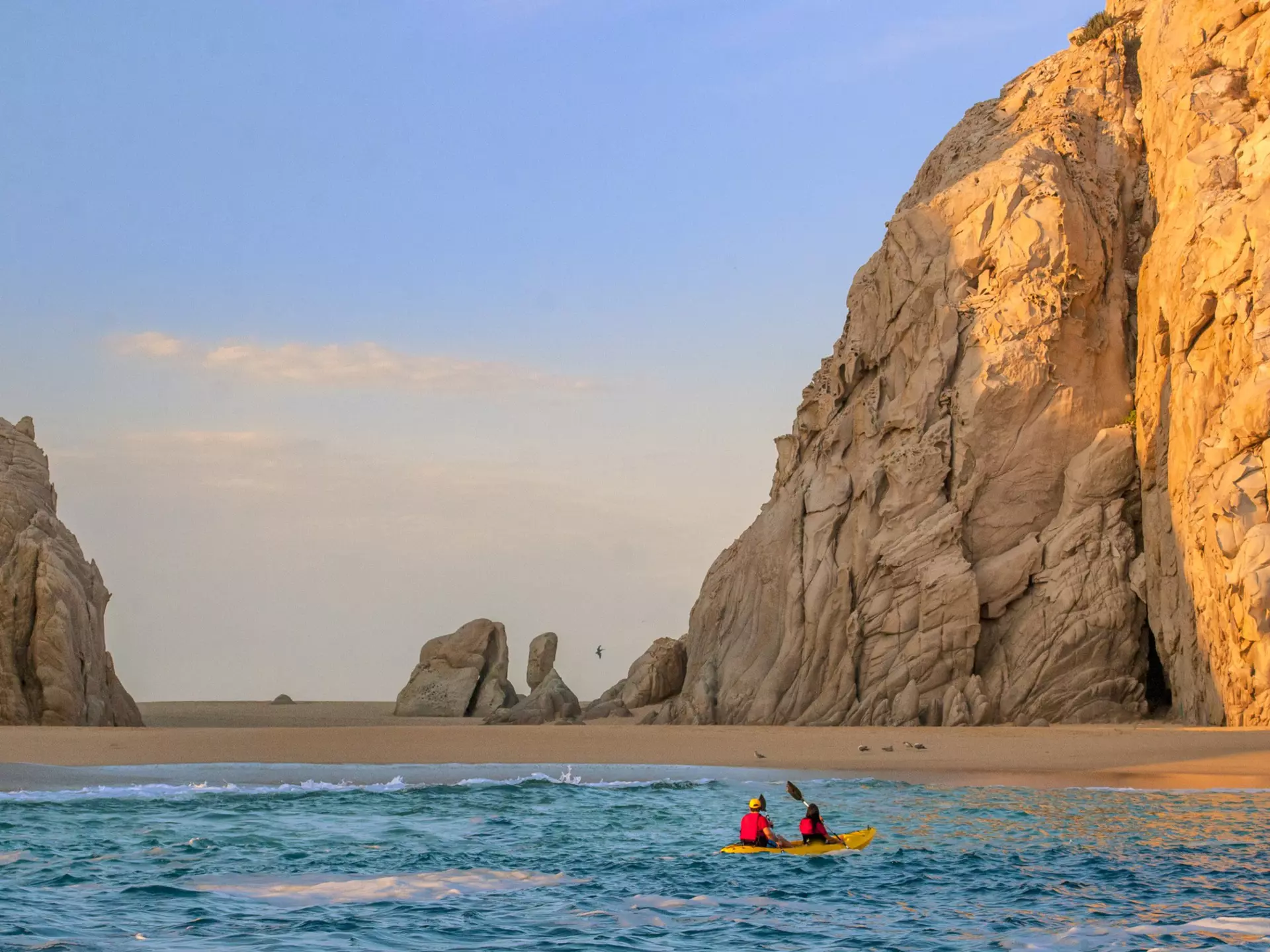 Two people in a kayak paddle towards Lover's Beach in Los Cabos
