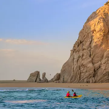Two people in a kayak paddle towards Lover's Beach in Los Cabos