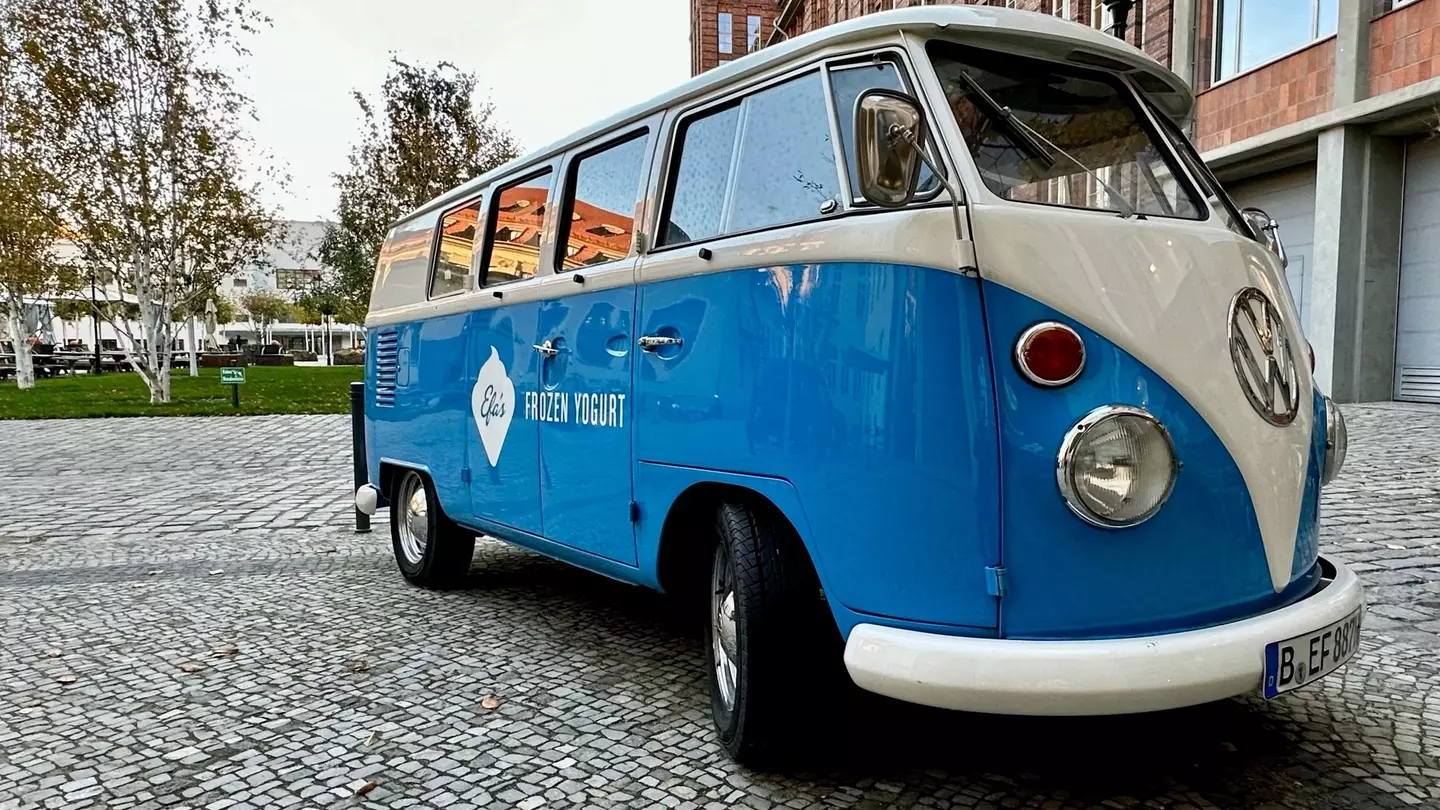 An orange VW camper cruises down a two-lane highway
